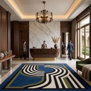 May include: A large rectangular area rug featuring a bold geometric pattern in blue, olive green, black, and cream. The design consists of concentric curved lines and solid color blocks, creating a modern visual focal point in a hotel lobby.