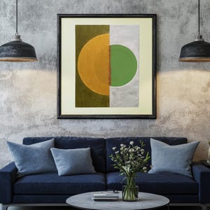 May include: A framed square wall art piece featuring a split composition. The left side is a deep olive green with a large golden yellow semi-circle. The right side is a light gray with a vibrant green circle, separated by a textured rust-colored line.