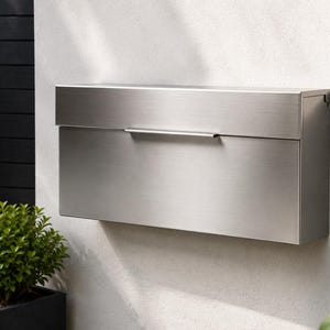 May include: A rectangular wall-mounted mailbox made of brushed stainless steel. The mailbox features a clean, flat front panel with a horizontal handle centered on the top lid, which lifts to reveal the mail slot. The design is simple and functional.
