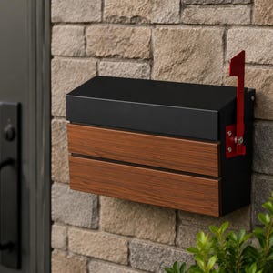 Puede incluir: Un buz&oacute;n de pared con una parte superior de metal negro mate y un panel frontal con acabado de veta de madera. La unidad rectangular incluye una bandera de metal rojo brillante unida al lado derecho, montada sobre una pared de piedra clara.