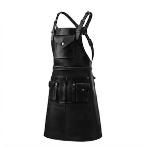 Peut inclure: Un tablier en cuir noir doté d'un système de bretelles croisées réglables avec des boucles en métal. L'avant comprend une poche de poitrine avec fermeture à pression et trois poches utilitaires inférieures avec boutons-pression et lanières.