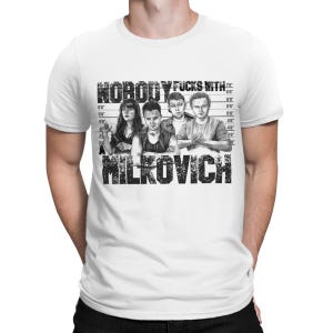 May include: A white short-sleeved t-shirt featuring a black and white graphic print of four individuals in a police lineup. The text reads NOBODY FUCKS WITH A MILKOVICH, with a height measurement chart in the background behind the figures.