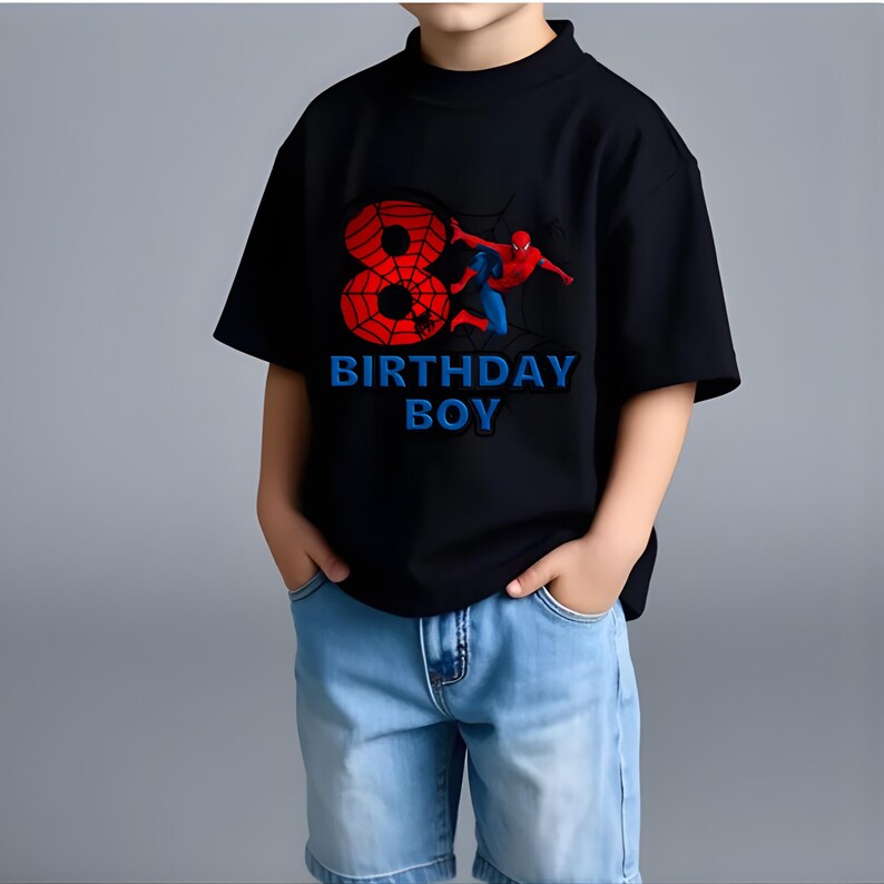 May include: A black short-sleeved t-shirt featuring a large red number eight designed with a spiderweb pattern, a graphic of the character Spider-Man, and the blue text "BIRTHDAY BOY" printed on the front center of the garment.