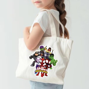 May include: A white canvas tote bag featuring a colorful graphic print of Marvel Spidey and His Amazing Friends characters, including Spider-Man, Ghost-Spider, Spin, Hulk, Black Panther, and Rhino, with the show title text printed in red and yellow.