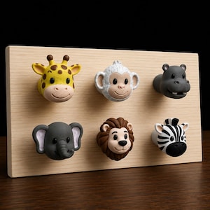 May include: A rectangular light-colored wooden board featuring six animal-shaped knobs arranged in two rows. The knobs depict a yellow giraffe, a white monkey, a gray hippopotamus, a gray elephant, a brown lion, and a black and white zebra.