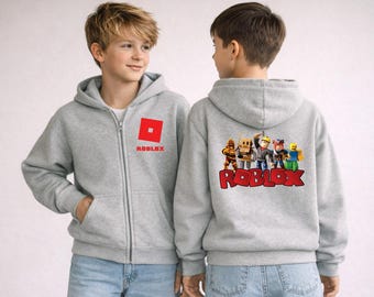 May include: A light gray zip-up hoodie featuring the Roblox logo on the front and a graphic of Roblox characters on the back. The hoodie has a hood and front pockets. The Roblox logo is a red square with a white square in the center.