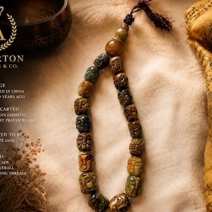 Peut inclure: Un chapelet de 18 perles de prière bouddhistes en jade néphrite sculptées à la main, chacune représentant un visage unique. Les perles sont disposées en boucle avec un pompon marron foncé au sommet. Longueur des perles 28 cm, longueur totale 34 cm.