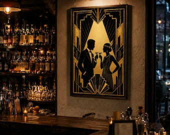 May include: Art Deco style framed print featuring a black and gold design of a couple toasting with cocktails. The artwork is set against a neutral wall in a dimly lit bar setting, with bottles and glassware visible.