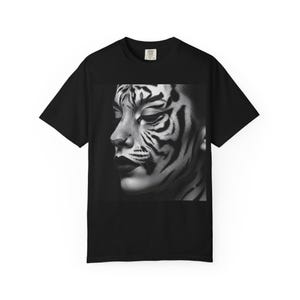 Könnte beinhalten: Schwarzes T-Shirt mit einem Schwarz-Weiß-Bild eines Gesichts mit Tigerstreifen. Die Person hat dunklen Lippenstift und geschlossene Augen. Das Bild ist mittig auf der Vorderseite des T-Shirts platziert.