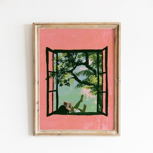 May include: A framed art print featuring a pink wall with an open black window frame. Through the window, a figure in a striped shirt is lying down reading a book under the green leaves of a tree against a light blue sky background.