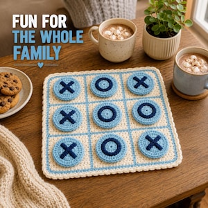 Puede incluir: Un tablero de tres en raya de ganchillo de color crema con líneas de cuadrícula azul claro. El juego incluye piezas circulares en azul claro con símbolos X y O cosidos en azul oscuro. El texto "FUN FOR THE WHOLE FAMILY" es visible.