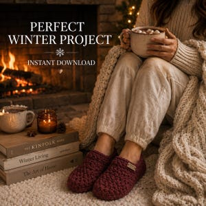 May include: A pair of dark maroon crochet slippers with a small rectangular tag on the side. The slippers are worn by a person sitting near a fireplace, holding a ceramic mug, with books and a candle nearby. Text reads PERFECT WINTER PROJECT.