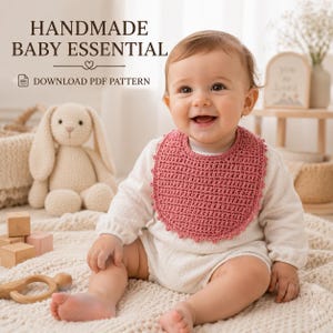 Può includere: Una bavaglino per neonati all'uncinetto color rosa polvere con bordo smerlato, indossato sopra una tutina bianca a maniche lunghe. L'immagine include il testo HANDMADE BABY ESSENTIAL e DOWNLOAD PDF PATTERN, indicando un modello digitale per l'accessorio.