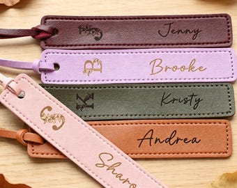 May include: Five rectangular leather bookmarks with stitched edges and matching leather tassels. Each bookmark features a unique floral-adorned initial and a name engraved in script: Jenny, Brooke, Kristy, Andrea, and Sharon in various colours.