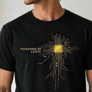 Può includere: Una t-shirt nera con una grafica color oro raffigurante un chip di processore centrale con linee di circuito stampato radianti. A sinistra della grafica, il testo "POWERED BY LOGIC" è stampato in un carattere sans-serif color oro.