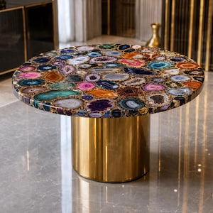 May include: A round table featuring a tabletop composed of numerous multicolored agate slices in shades of blue, purple, pink, orange, and brown. The table is supported by a single, cylindrical, polished gold-colored metal pedestal base.