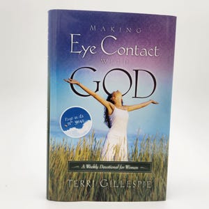 Puede incluir: Un libro titulado Making Eye Contact with GOD de Terri Gillespie. La portada muestra a una persona con un vestido blanco en un campo con los brazos extendidos hacia un cielo azul. Una insignia circular indica el texto Now in its 18th year.