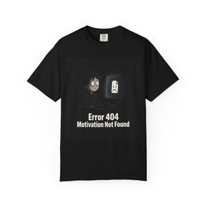 Könnte beinhalten: Ein schwarzes Kurzarm-T-Shirt mit einer Grafik einer Person, die vor einem Computer mit einem traurigen Dateisymbol auf dem Bildschirm sitzt. Unter der Grafik steht der Text Error 404 Motivation Not Found in weißen Buchstaben.