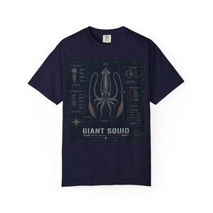 May include: A navy blue short-sleeve t-shirt featuring a detailed scientific illustration of a giant squid. The graphic includes technical diagrams, labels, and the text "GIANT SQUID" and "DEEP SEA LEVIATHAN" printed in a white, distressed font.