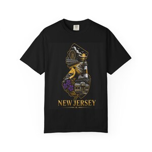 May include: A black short-sleeve t-shirt featuring a graphic of the state of New Jersey. The design includes a ferris wheel, a lighthouse, a bird, purple flowers, and a diner. The text NEW JERSEY is printed in gold at the bottom of the graphic.
