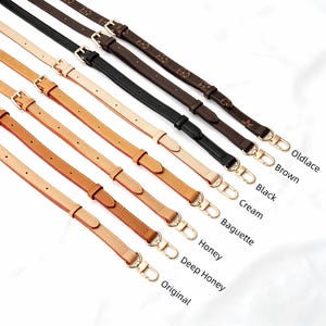 May include: A selection of leather bag straps in shades like brown, black, and cream. Each strap has gold-coloured metal hardware and a buckle. The image shows the straps labelled with their respective colours.
