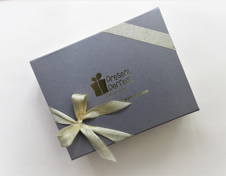 May include: A gray gift box with a gold ribbon and a gold logo that reads 'Present Perfect Creations' and 'presentperfectcreations.com'.