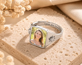 May include: A silver-toned signet ring featuring a square face with a color photograph of a smiling person. The inner band is engraved with the text 'Love you forever'. The ring includes a small, clear, star-shaped accent stone on the side.