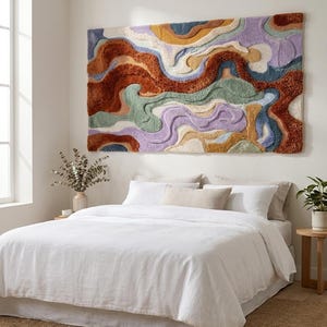 May include: A large rectangular wall hanging featuring a tufted, high-pile texture with an abstract, layered design. The piece displays organic, flowing shapes in a palette of rust orange, sage green, lavender, mustard yellow, and cream.