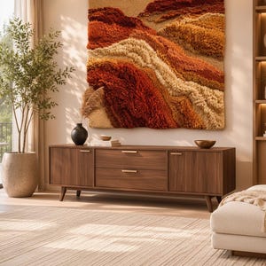 May include: A large square wall hanging featuring a textured, tufted landscape design in shades of rust, burnt orange, cream, and tan. The piece displays layered, wavy patterns that mimic geological formations, mounted above a wooden media console.