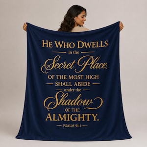 May include: A navy blue fleece blanket featuring gold text that reads: He Who Dwells in the Secret Place, OF THE MOST HIGH SHALL ABIDE under the Shadow OF THE ALMIGHTY. PSALM 91:1. The blanket has a soft texture and a rectangular shape.