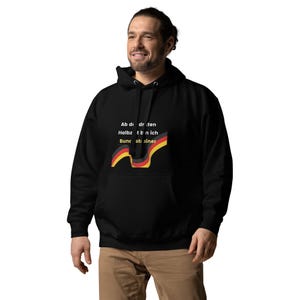 Puede incluir: Sudadera con capucha negra con bolsillo delantero y capucha con cordón. La sudadera presenta texto y un gráfico con los colores de la bandera alemana. El texto dice "Ab die dritten Halbzeit bin ich Bundstrainer."