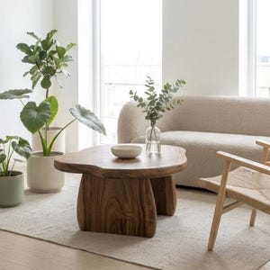 May include: A low, organic-shaped wooden coffee table with a thick, natural-grain top and two sturdy, curved slab legs. The table is crafted from solid wood with a warm brown finish, featuring a smooth, irregular edge that mimics natural wood forms.