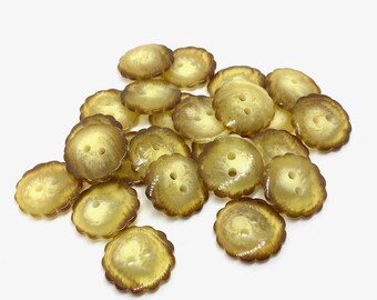 May include: A pile of amber and brown translucent buttons with a scalloped edge. Each button has two holes for sewing and a slightly domed shape. The buttons are scattered on a white background.