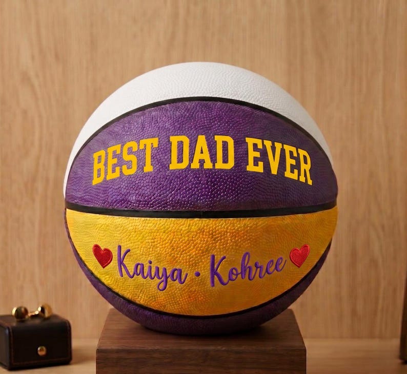 May include: A basketball featuring a white top panel, a purple middle panel with the yellow text BEST DAD EVER, and a yellow bottom panel. The bottom panel displays the purple text Kaiya &bull; Kohree flanked by two small red heart icons.