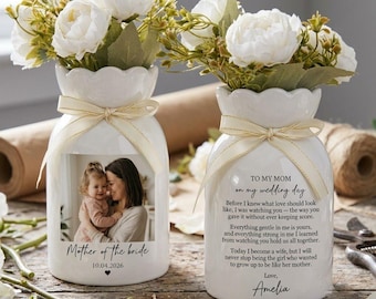 May include: Two white ceramic vases with scalloped rims and cream ribbons. One vase features a photo of a child and adult with the text Mother of the bride 10.04.2026. The other vase displays the text TO MY MOM on my wedding day with a poem.