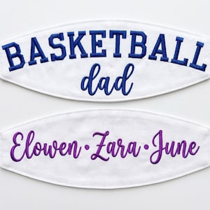 May include: Two white fabric patches with embroidered text. The top patch features the word BASKETBALL in blue block letters and the word dad in blue script. The bottom patch features the names Elowen, Zara, and June in purple script.
