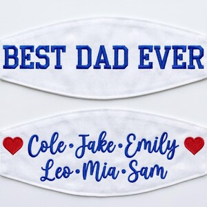 May include: Two white fabric face masks with blue embroidery. The top mask features the text BEST DAD EVER in block letters. The bottom mask displays the names Cole, Jake, Emily, Leo, Mia, and Sam in script, flanked by two red embroidered hearts.