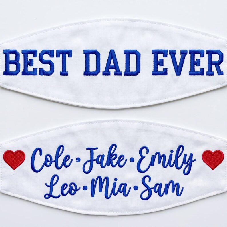 May include: Two white fabric face masks with blue embroidery. The top mask features the text BEST DAD EVER in block letters. The bottom mask displays the names Cole, Jake, Emily, Leo, Mia, and Sam in script, flanked by two red embroidered hearts.