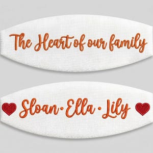 May include: Two white fabric ovals featuring orange embroidered text. The top oval reads The Heart of our family. The bottom oval displays the names Sloan, Ella, and Lily in orange text, flanked by a small red embroidered heart on each side.