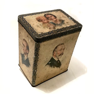 Könnte beinhalten: Vintage Blechdose mit Bildern einer königlichen Familie, darunter eine Frau und ein Kind auf dem Deckel und ein Mann an der Seite. Die Dose hat einen blauen und goldenen Rand.