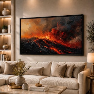 Op de afbeelding: Groot ingelijst kunstwerk dat een vurige vulkaanuitbarsting boven een donkere oceaan uitbeeldt. Het schilderij toont levendige rood-, oranje- en zwarttinten, waardoor een dramatische scène ontstaat. Het kunstwerk wordt getoond boven een beige bank.