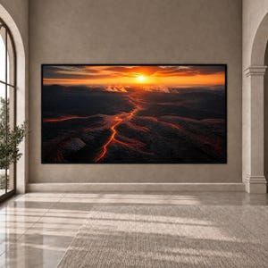Peut inclure: Une grande impression d'art mural rectangulaire représentant un paysage panoramique d'une éruption volcanique au coucher du soleil. De la lave orange vif coule sur un terrain sombre et accidenté sous un ciel doré, encadrée d'un bord noir.