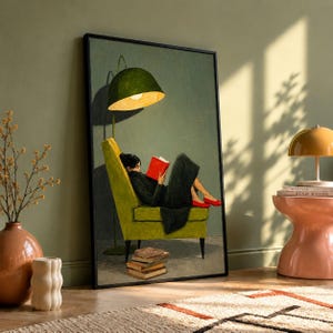 Puede incluir: Una lámina de arte enmarcada que muestra a una persona sentada en un sillón verde lima bajo una gran lámpara de pie verde. La persona viste un conjunto negro y zapatos rojos mientras lee un libro rojo. Una pila de cuatro libros marrones está en el suelo.