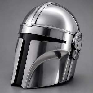 May include: A metallic silver helmet with a sleek, futuristic design. The helmet features a visor with a black vertical stripe and a curved shape. The top has a raised central ridge and side details. The helmet is likely a prop or costume piece.