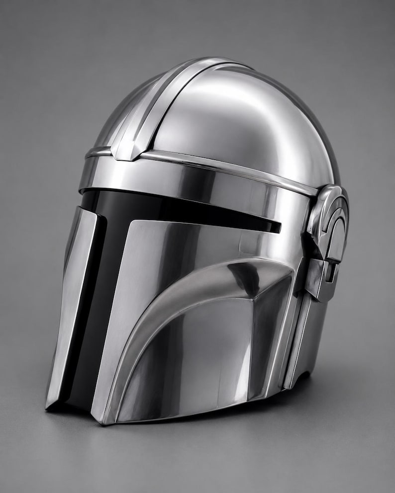 May include: A metallic silver helmet with a sleek, futuristic design. The helmet features a visor with a black vertical stripe and a curved shape. The top has a raised central ridge and side details. The helmet is likely a prop or costume piece.