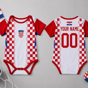 May include: A white and red checkered baby bodysuit featuring the Croatian coat of arms on the front and the text YOUR NAME with the number 00 on the back. The garment has short red sleeves and red trim around the neckline and leg openings.