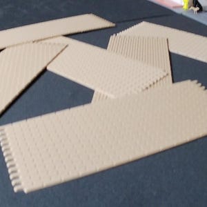 Può includere: Piastrelle per pavimenti in schiuma beige ad incastro con superficie strutturata e bordi ad incastro. Le piastrelle rettangolari sono disposte su una superficie blu scuro. Le piastrelle sono progettate per incastrarsi e creare un pavimento imbottito.