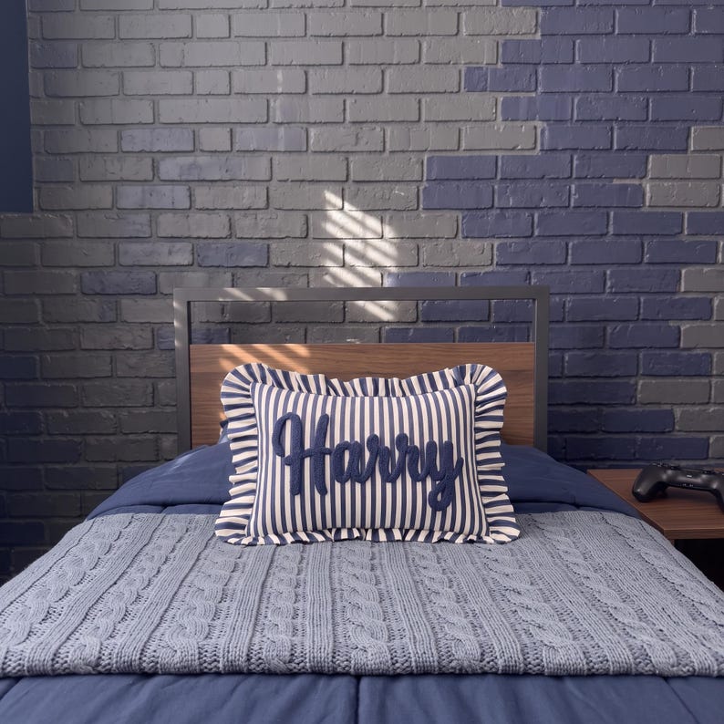 a bedroom with a bed, a pillow with the name "Harry" on it, and a brick wall in the background.