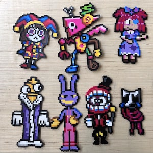 May include: A collection of seven pixel art figures, each with a unique design and color scheme. The figures include a jester, a pink robot-like character, a girl in a purple dress, a king, a purple rabbit, a red-faced character, and a raccoon.