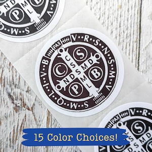 May include: Three circular stickers featuring the Saint Benedict medal design in dark brown on a white background. The design includes a central cross with the letters C S S M D and N D S M D, surrounded by the letters V R S N S M V and S M Q L I V B.